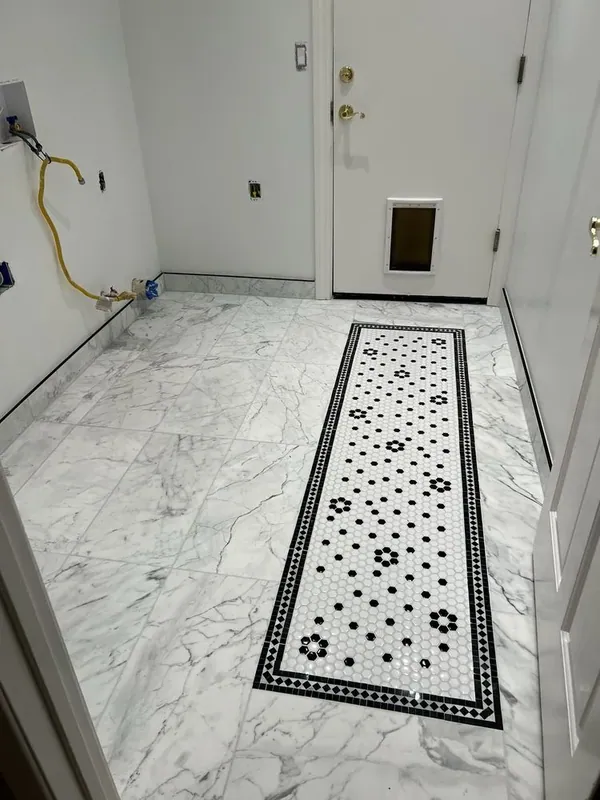 Laundry room floor of large marble-look tiles with a black-and-white hex mosaic runner
