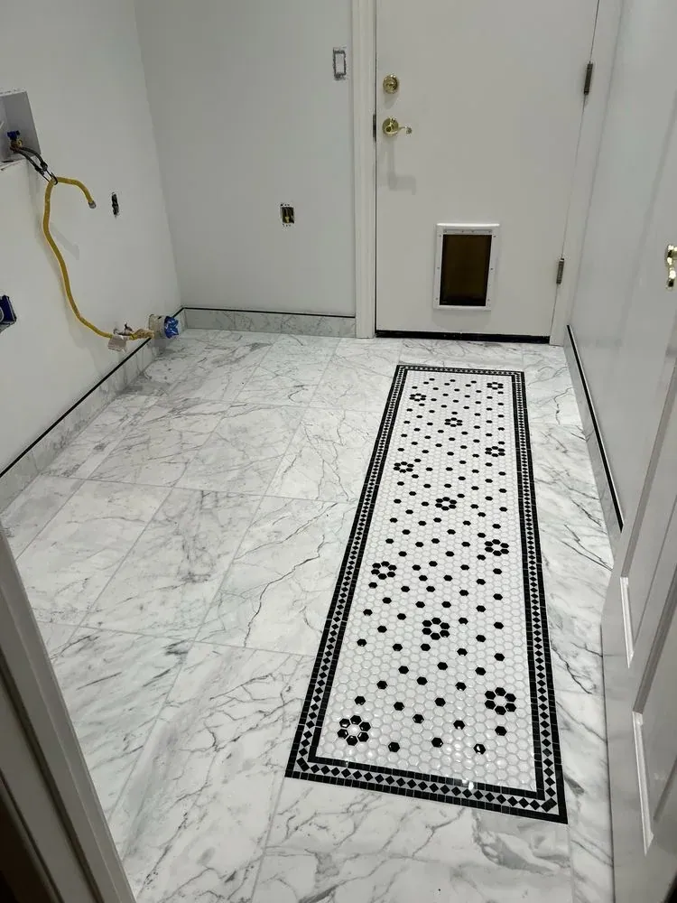 Laundry room floor of large marble-look tiles with a black-and-white hex mosaic runner