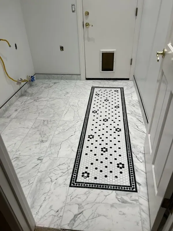 The same laundry room floor seen from the doorway, with the mosaic runner leading to the exterior door