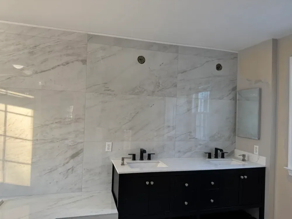 Large white marble-look wall tile behind a black double vanity