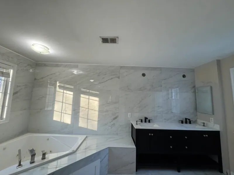 Corner jetted tub in a tiled platform beside the double vanity