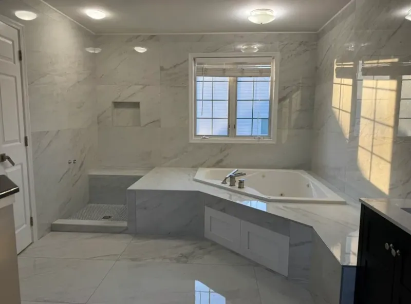 Shower area with a bench and niche next to the tiled tub platform