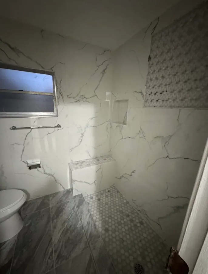 Shower area with the mosaic panel, niche and bench seen from the doorway