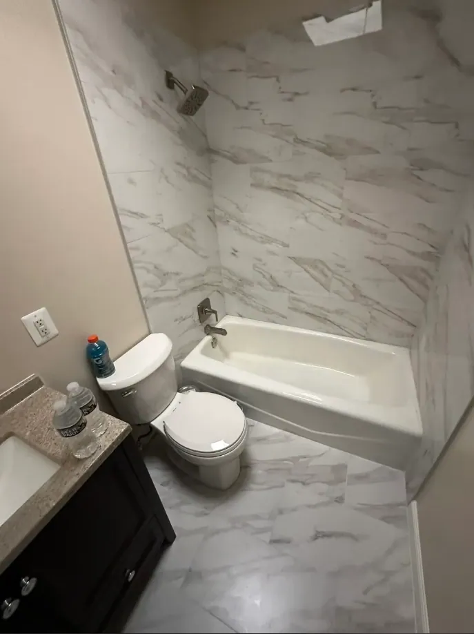Tub surround and floor in white marble-look tile with gray diagonal veining
