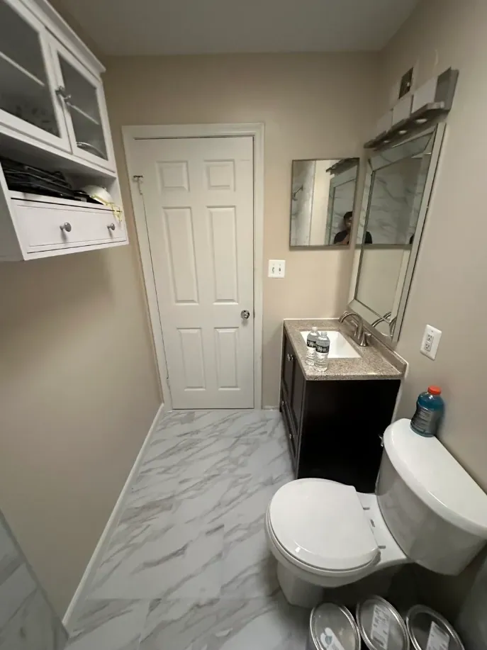 Bathroom floor in white marble-look tile running from the door to the toilet